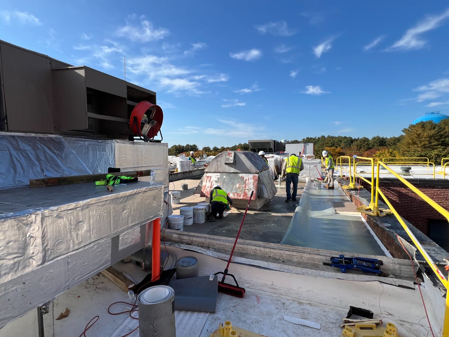 Crew installing white TPO membrane commercial roof
