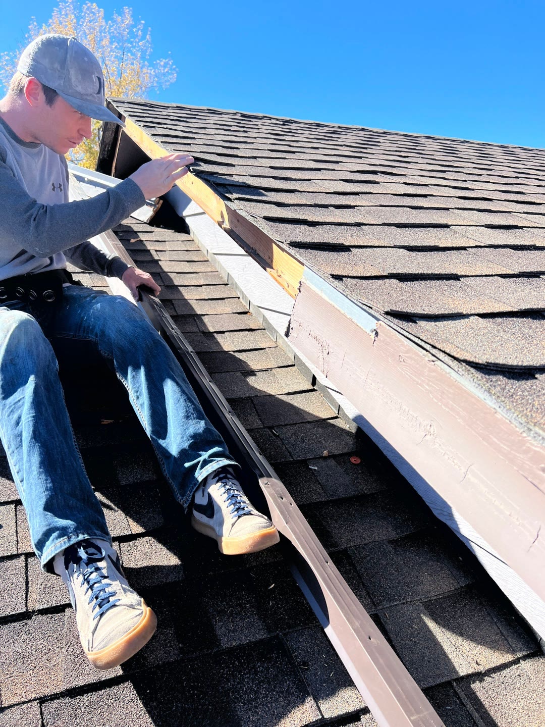 Pinnacle crew member repairing trim and fascia on roof ridge