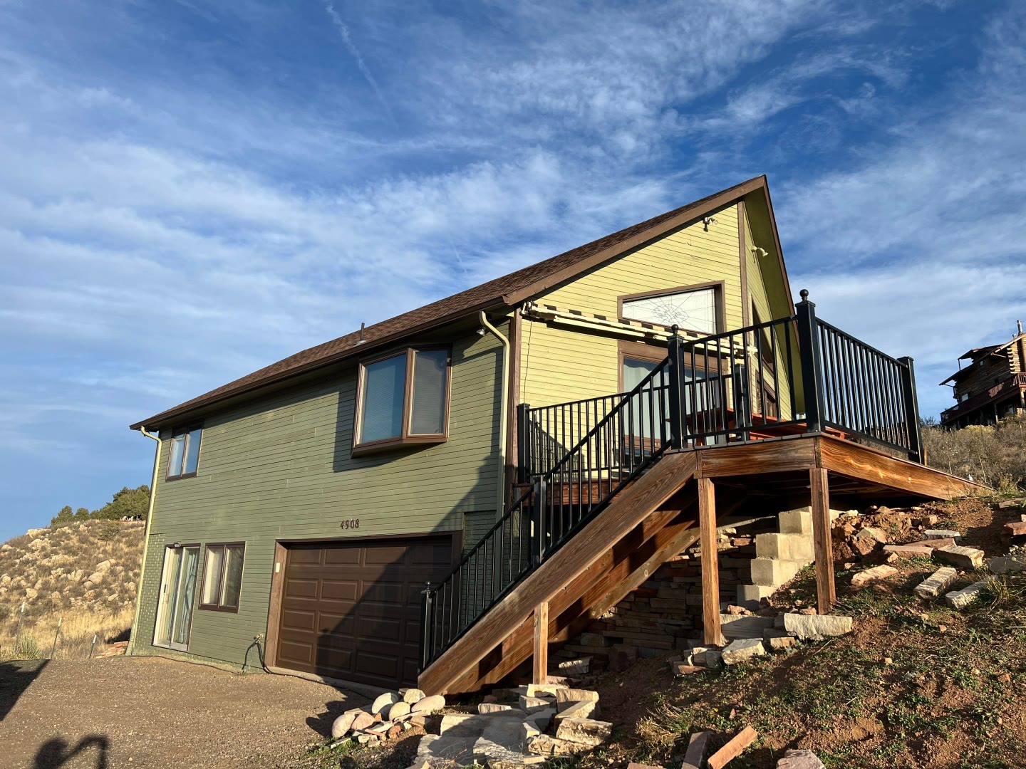 Hillside home after exterior painting green and yellow siding