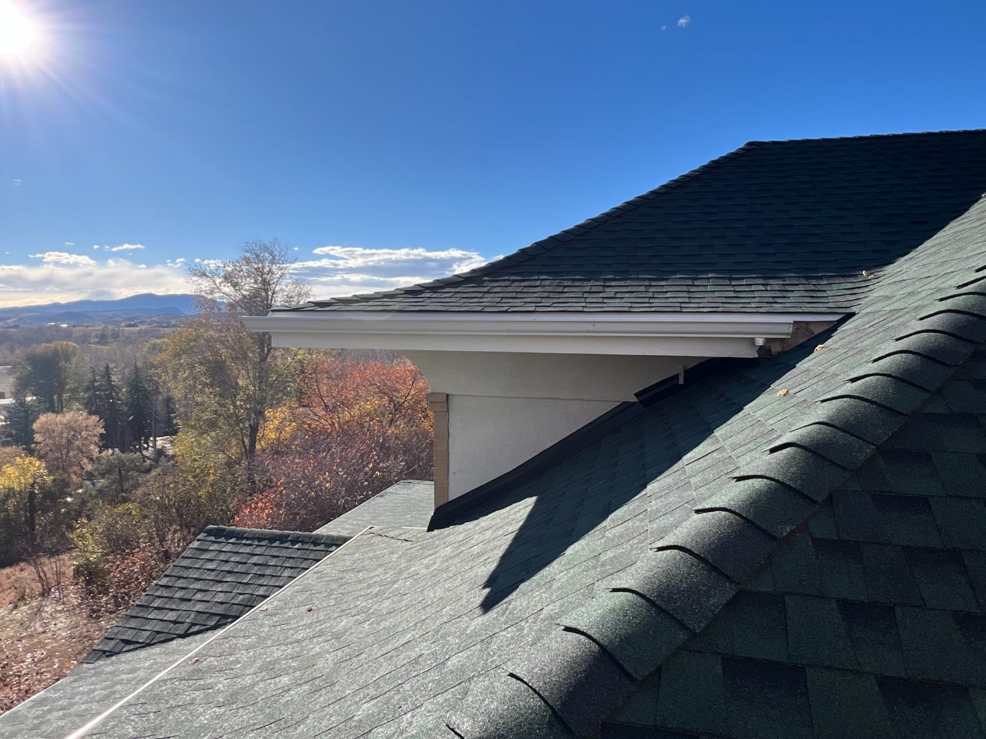 Completed shingle roof with new gutters and Colorado mountain view