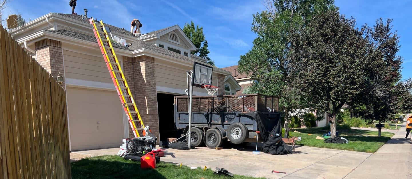 Pinnacle Home Restoration job site with yard sign crew on roof and dump trailer